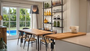 A modern kitchen with a wooden dining table, black chairs, and a built-in shelf with various glassware. - Villa Veronika – Stone design villa of tranquility (Vabriga)