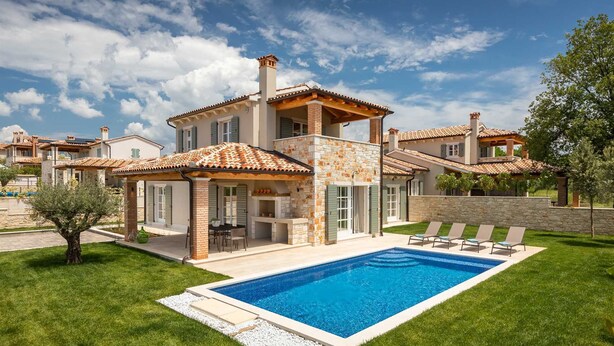 A two-story house with a swimming pool, a patio with chairs, and a garden. - Villa Veronika – Stone design villa of tranquility (Vabriga)