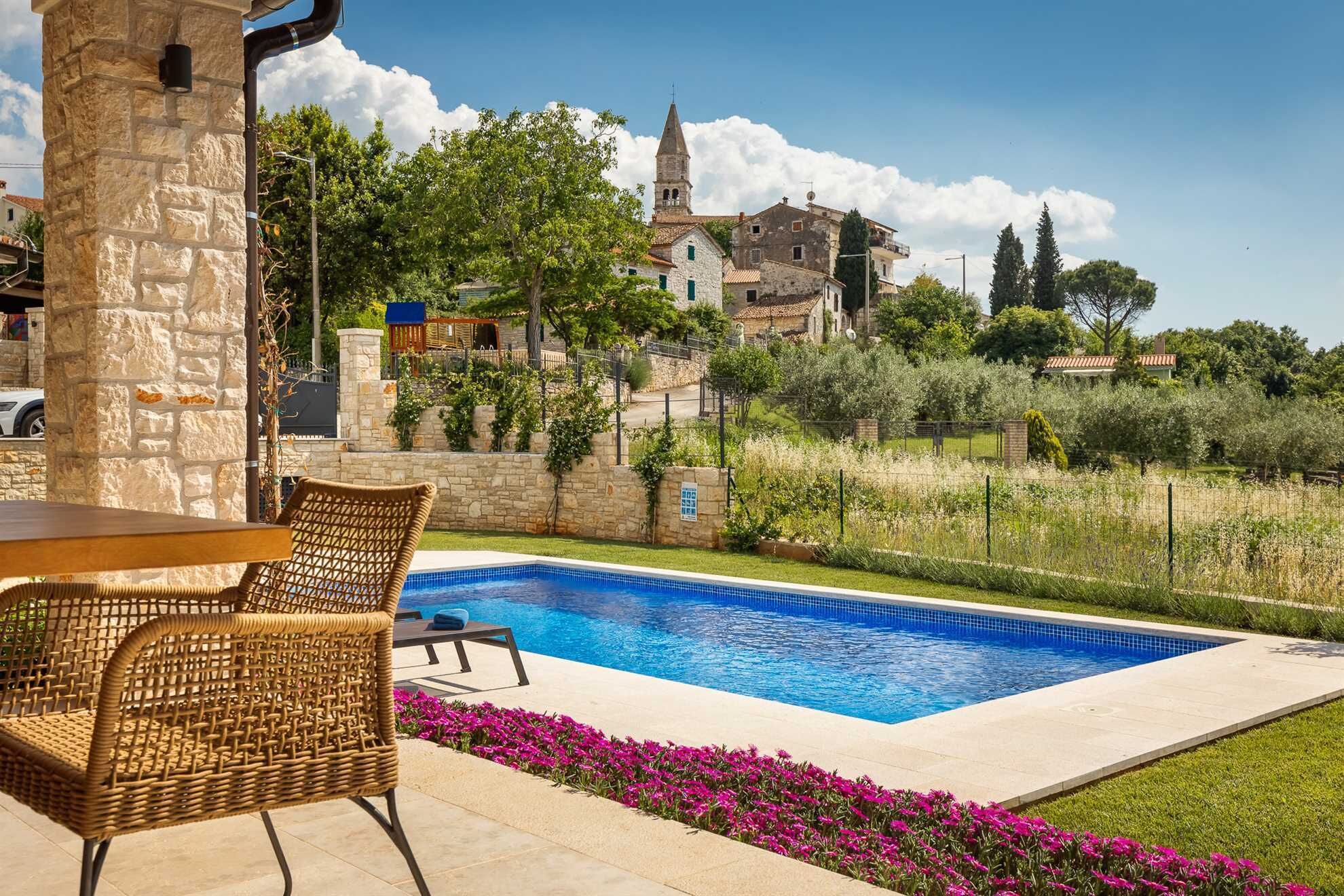 A swimming pool with a stone wall and a wicker chair.