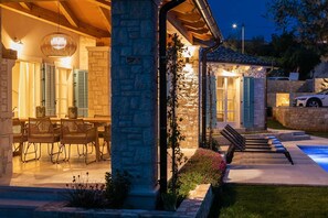 Une terrasse extérieure dotée d’un espace repas, de piliers en pierre et d’une piscine.