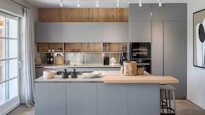 A modern kitchen with grey cabinets, a wooden countertop, and a built-in oven. - Villa Oaza – A Stone Oasis with Sea View (Vabriga)