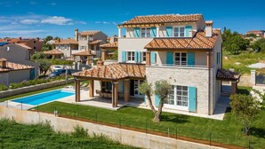 A two-story house with a swimming pool, stone facade, and multiple windows with shutters. - Villa Oaza – A Stone Oasis with Sea View (Vabriga)