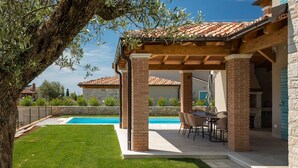 A covered patio with a pool, outdoor furniture, and a stone wall. - Villa Oaza – A Stone Oasis with Sea View (Vabriga)