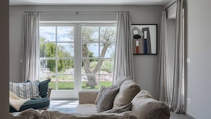 A living room with a large window, a sofa, and a framed artwork on the wall. - Villa Oaza – A Stone Oasis with Sea View (Vabriga)