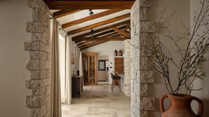 A stone-walled corridor with a wooden ceiling, leading to a kitchen area with a bar and seating. - Villa Olive View – Your Exclusive Retreat (Vabriga)