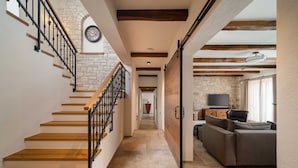 A staircase with wooden steps and black railings, leading to a living area with a sofa and a flat-screen TV. - Villa Olive View – Your Exclusive Retreat (Vabriga)