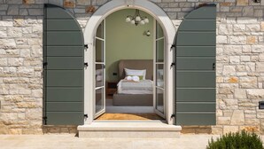 A bedroom with a bed, pillows, and a nightstand. - Villa Olive View – Your Exclusive Retreat (Vabriga)