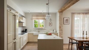 Une cuisine moderne dotée d’un îlot central, de meubles de rangement intégrés, d’une fenêtre offrant une belle vue et d’un coin repas avec une table et des chaises.