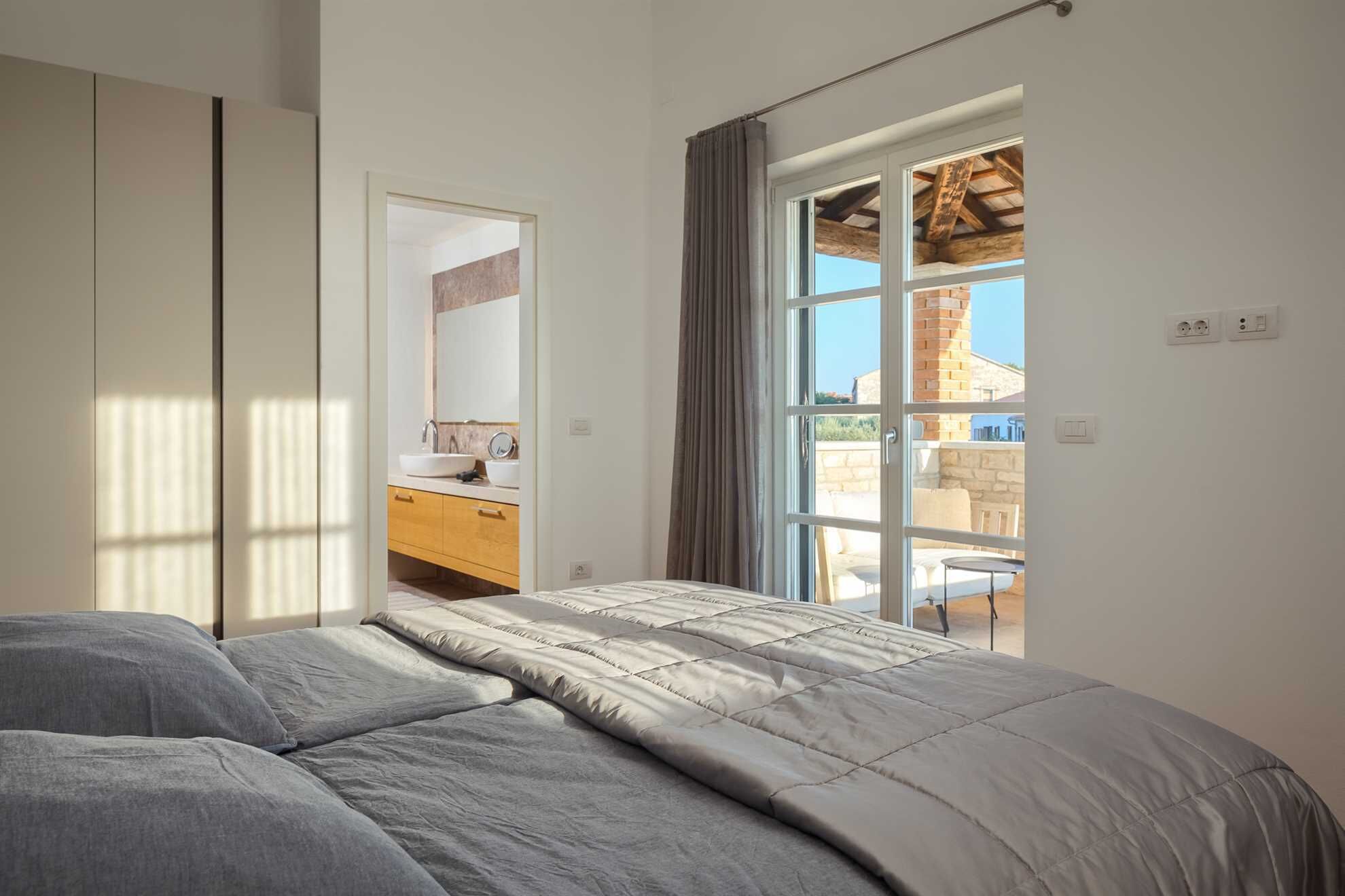 Une chambre avec un lit, une salle de bain avec un lavabo et une vue sur l’extérieur.