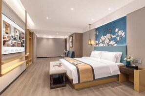 A modern hotel room with a large bed, bedside tables, a wall-mounted TV, and a decorative wall piece. - Magnolia Hotel (Nanjing Olympic Sports Center Branch) (Nanjing)