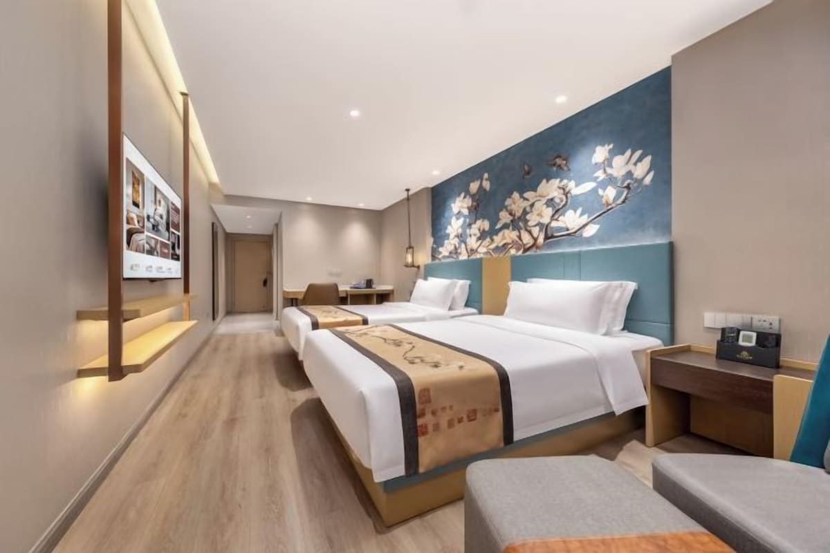 A hotel room with two beds, a desk, and a seating area.
