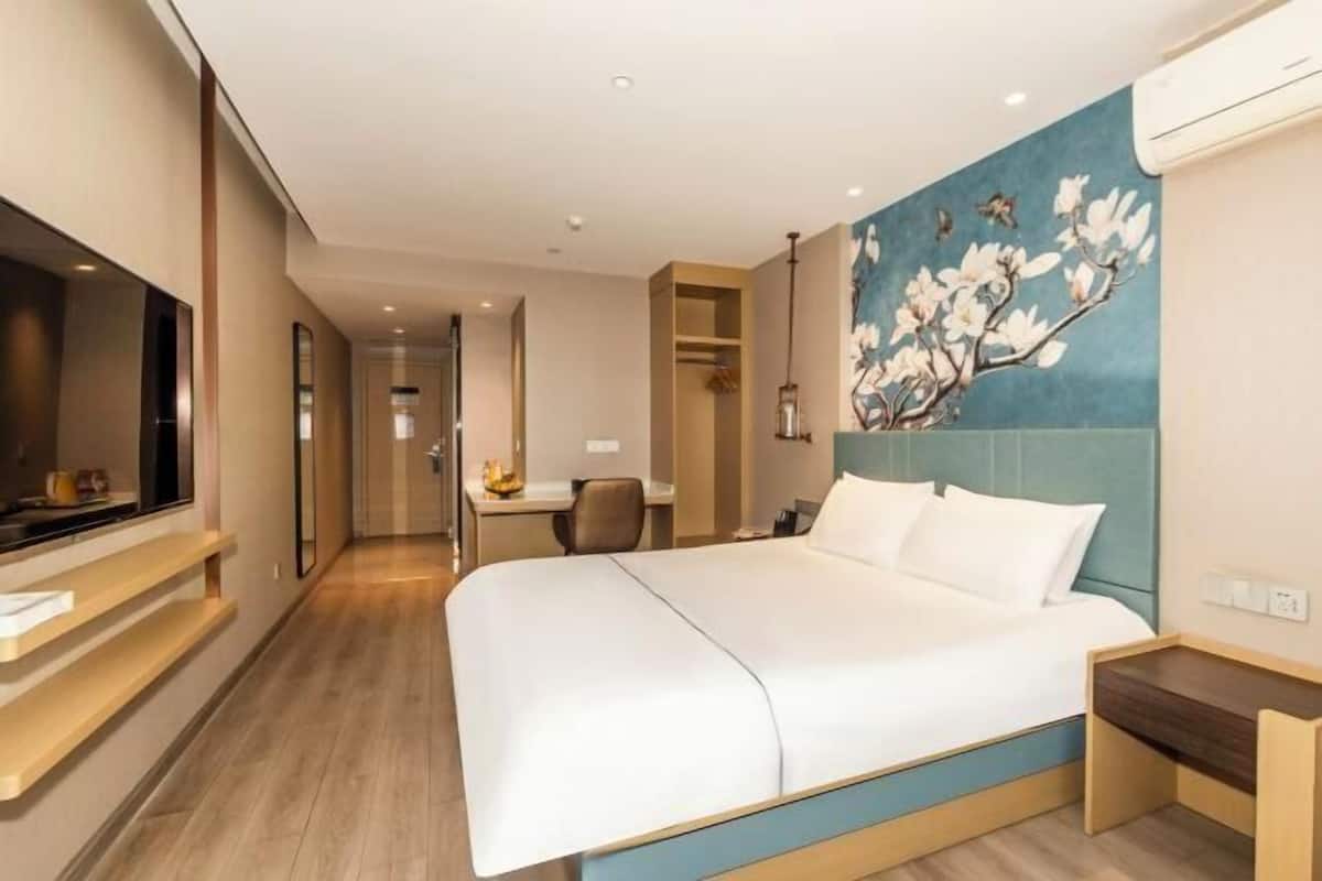 A hotel room with a bed, a desk, a chair, and a TV.