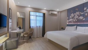 Ett hotellrum med en säng, ett skrivbord med en stol, en TV och en luftkonditioneringsanläggning.