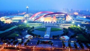 Un estadio grande y moderno con una estructura en forma de arco distintiva y una torre al fondo.