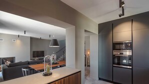 Une cuisine moderne dotée d’un four Bosch, d’un plan de travail en bois et d’un design minimaliste.