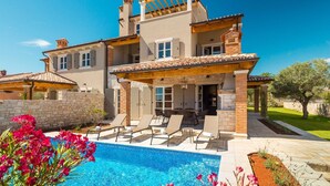 Une maison à deux étages avec une piscine, un espace salon extérieur et un jardin.
