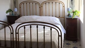 A bedroom with a four-poster bed, a nightstand with a lamp, a dresser with a vase of flowers, and a framed picture on the wall. - Nineteenth-century house with adjoining historic garden on the Stagnone of Marsala (Marsala)