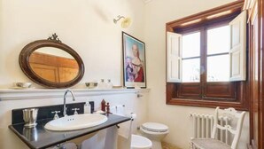 A bathroom with a sink, mirror, toilet, and a chair. - Nineteenth-century house with adjoining historic garden on the Stagnone of Marsala (Marsala)