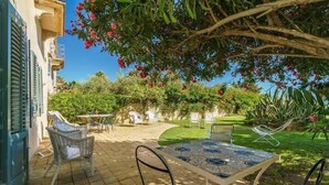 An outdoor patio with a table and chairs, surrounded by greenery and a building with shutters. - Nineteenth-century house with adjoining historic garden on the Stagnone of Marsala (Marsala)