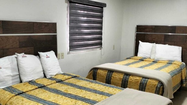 A hotel room with two beds, each with a headboard, a window with blinds, and a tiled floor. - HOTEL ECONOMICO (Tijuana)