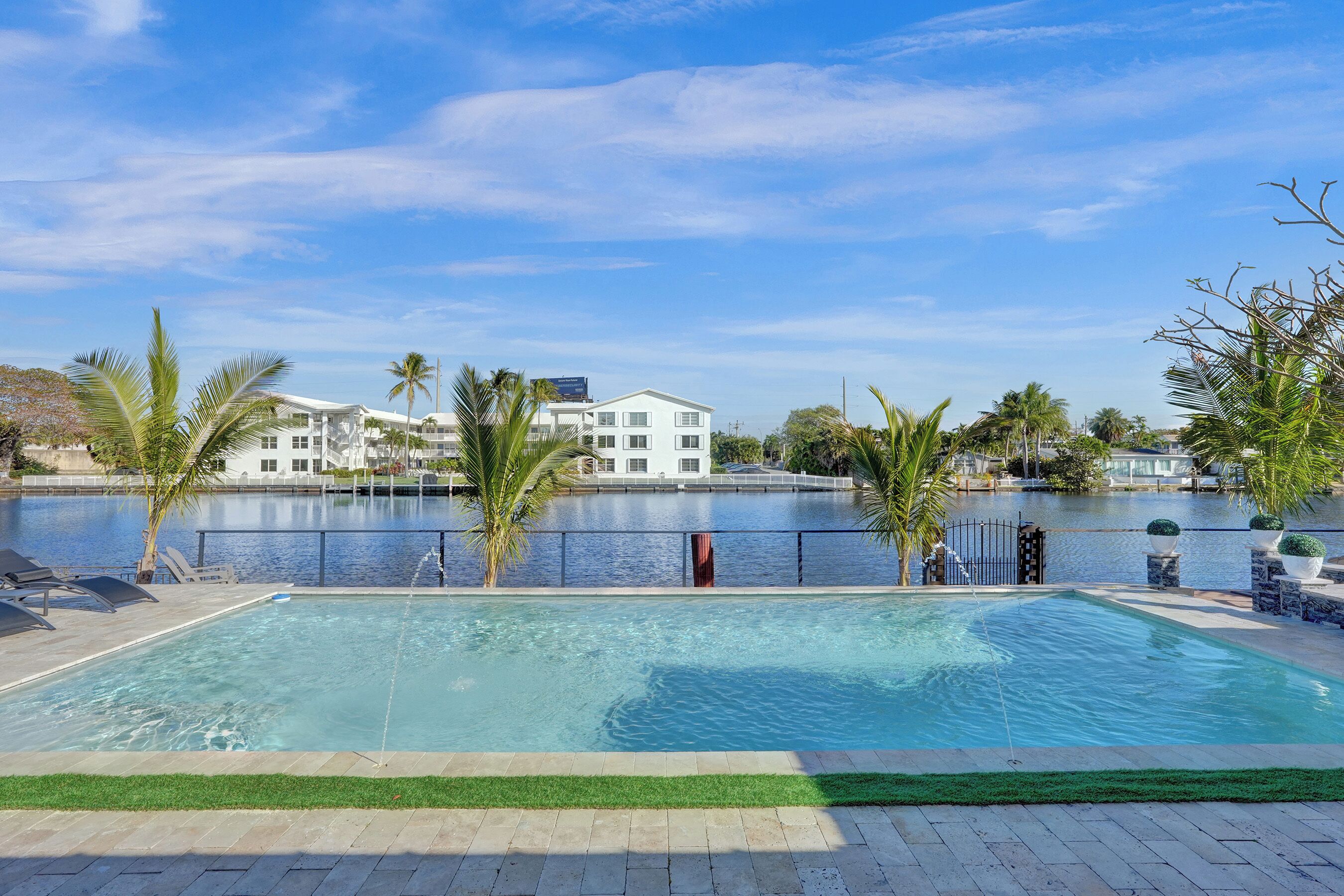 Una piscina con vistas a una masa de agua y edificios al fondo.