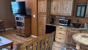 A rustic interior with wooden furniture, a television, and a kitchen area.