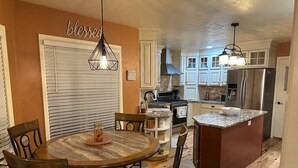 A kitchen with white cabinets, a central island, and a dining area with a round table and chairs.