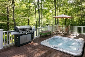 Een terras met een jacuzzi, een barbecue en tuinmeubilair.