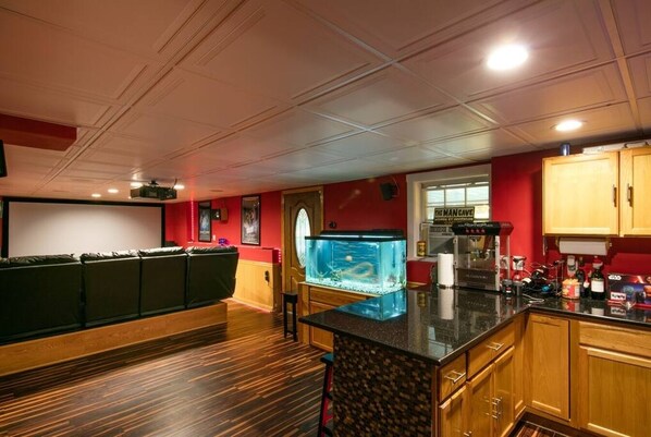 Zona de bar con acuario, armarios de madera y mostrador.