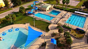 Vista aérea de una instalación acuática con varias piscinas, un tobogán de agua y una zona cubierta.