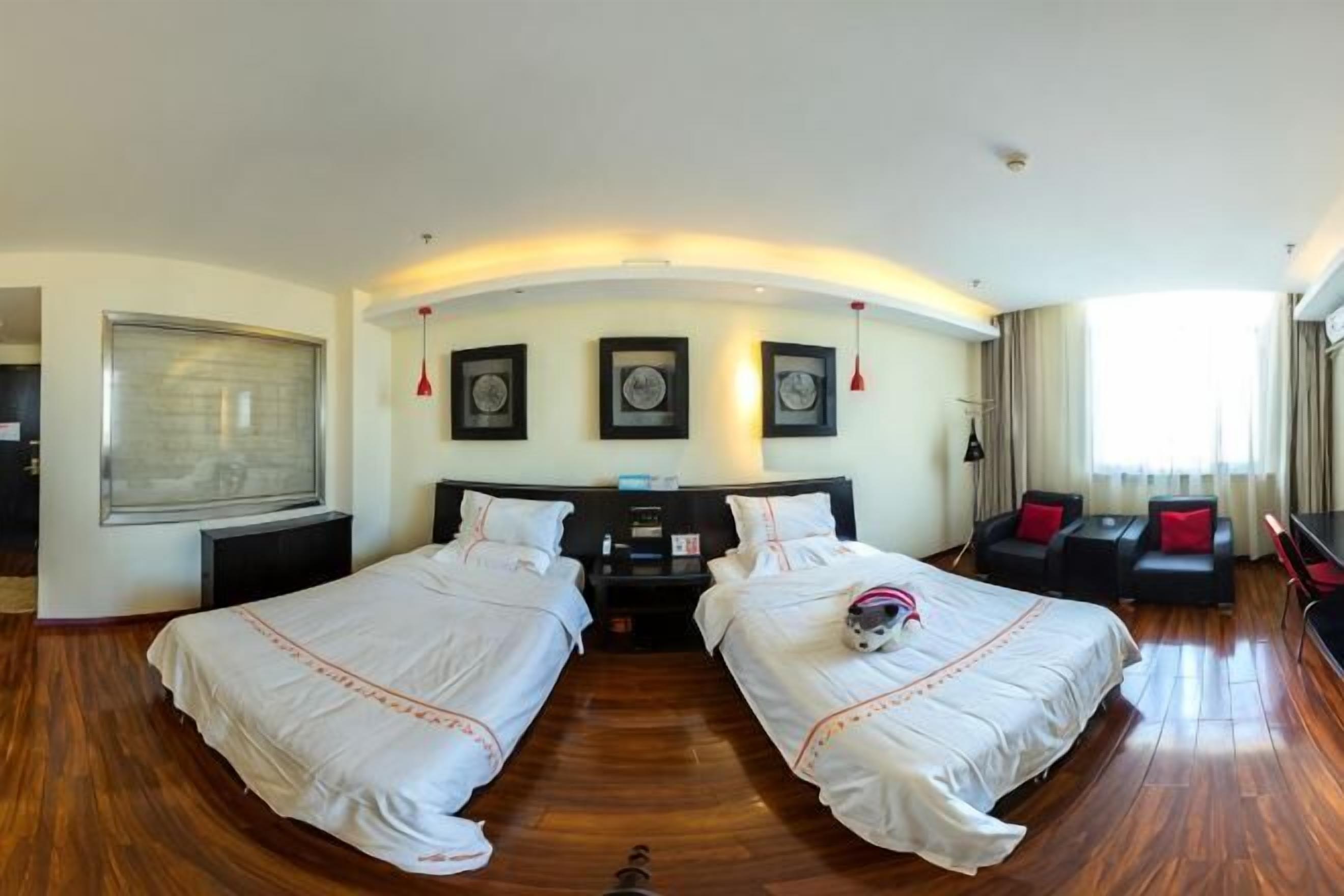 A hotel room with two beds, a desk, a chair, and a large window.
