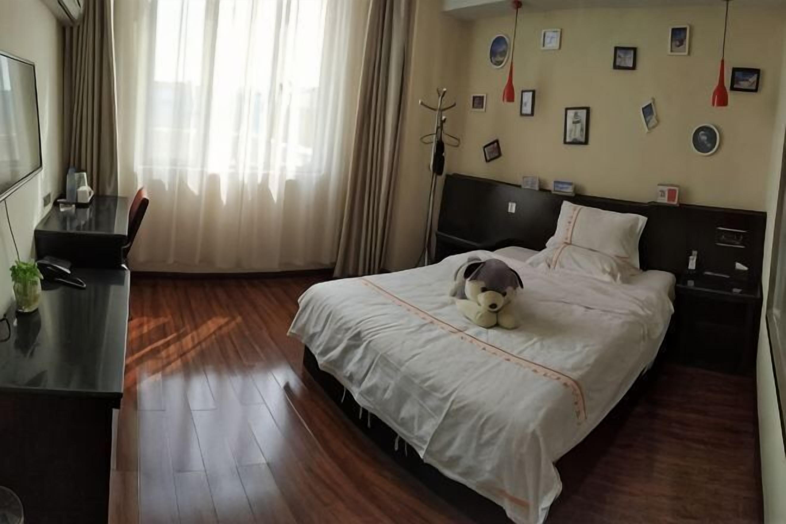 A hotel room with a bed, a desk, a chair, a TV, and a window with curtains.