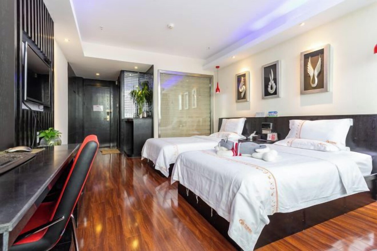 Una habitación de hotel con dos camas, un escritorio y una televisión.
