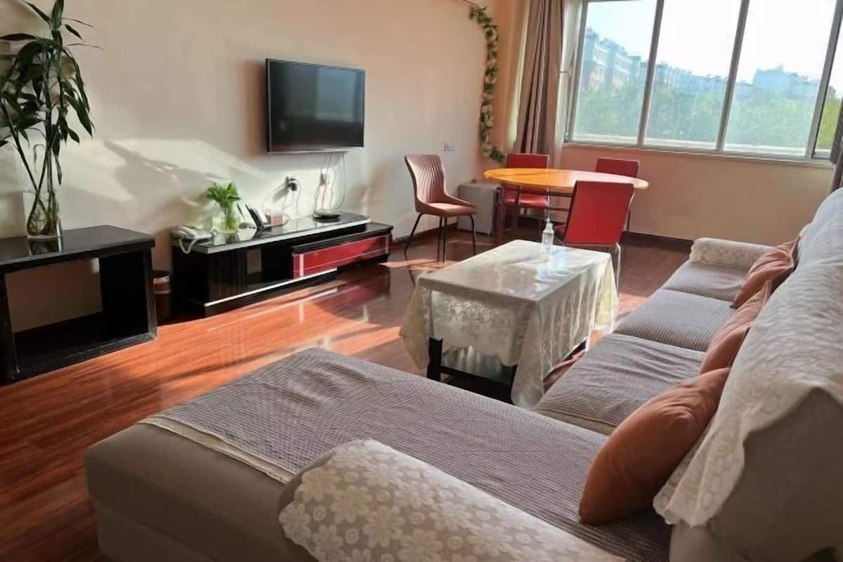 A living room with a sofa, a small table, a TV, and a window with a view.