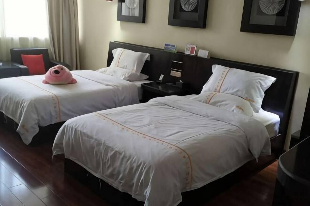 Two beds with white bedding and a nightstand with a lamp.