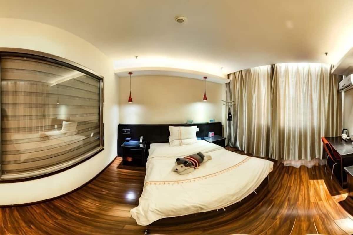 A circular room with a bed, bedside tables, a desk, and a large window.