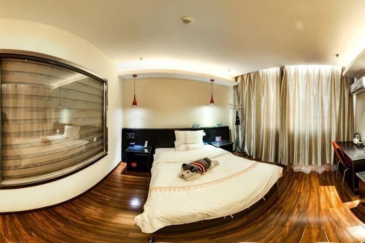 A circular room with a bed, bedside tables, a desk, and a large window.