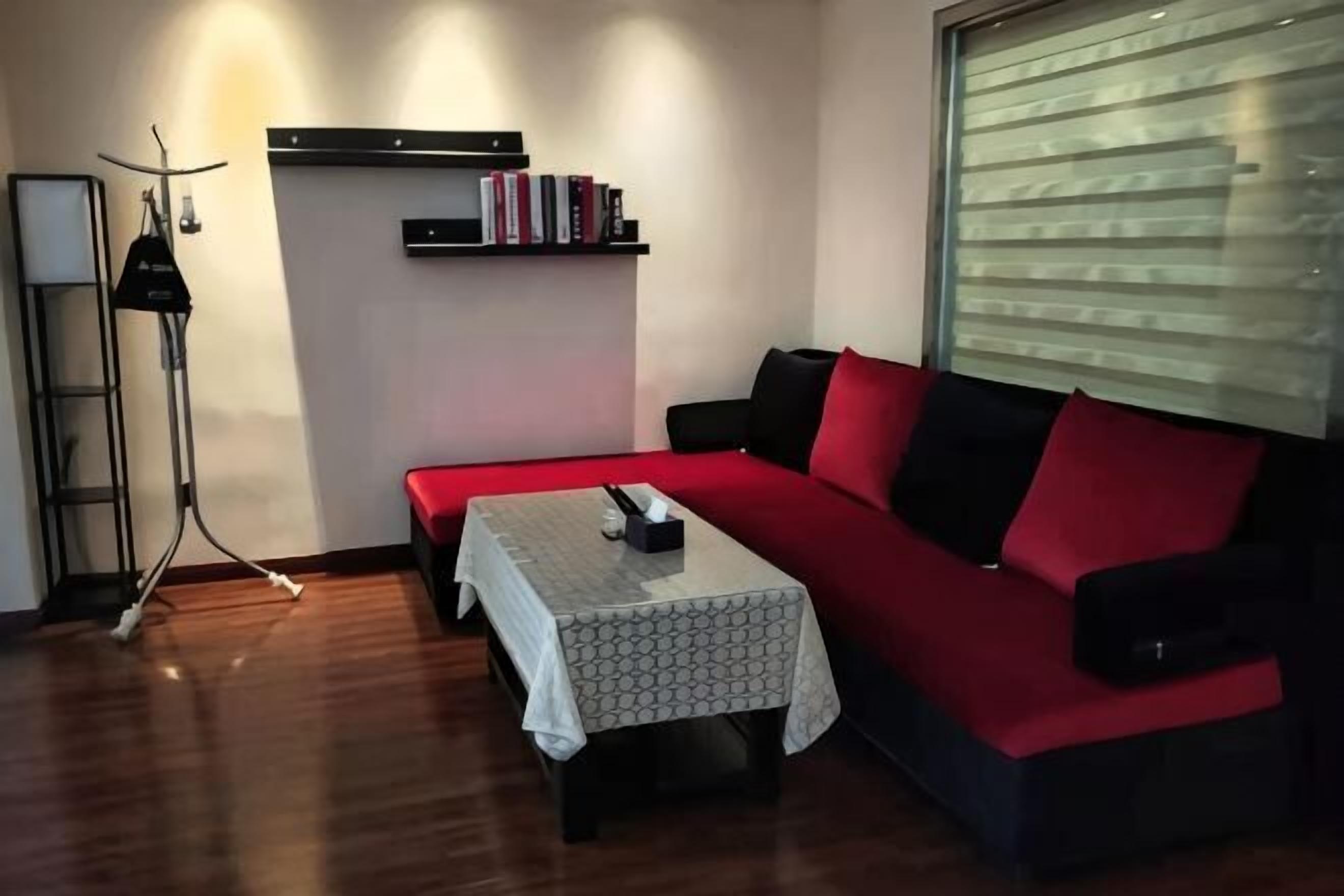 A living room with a sofa, a table, a bookshelf, and a floor lamp.
