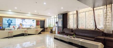 A hotel reception area with a reception desk, seating area, and large windows.