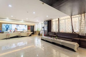 A hotel reception area with a reception desk, seating area, and large windows.
