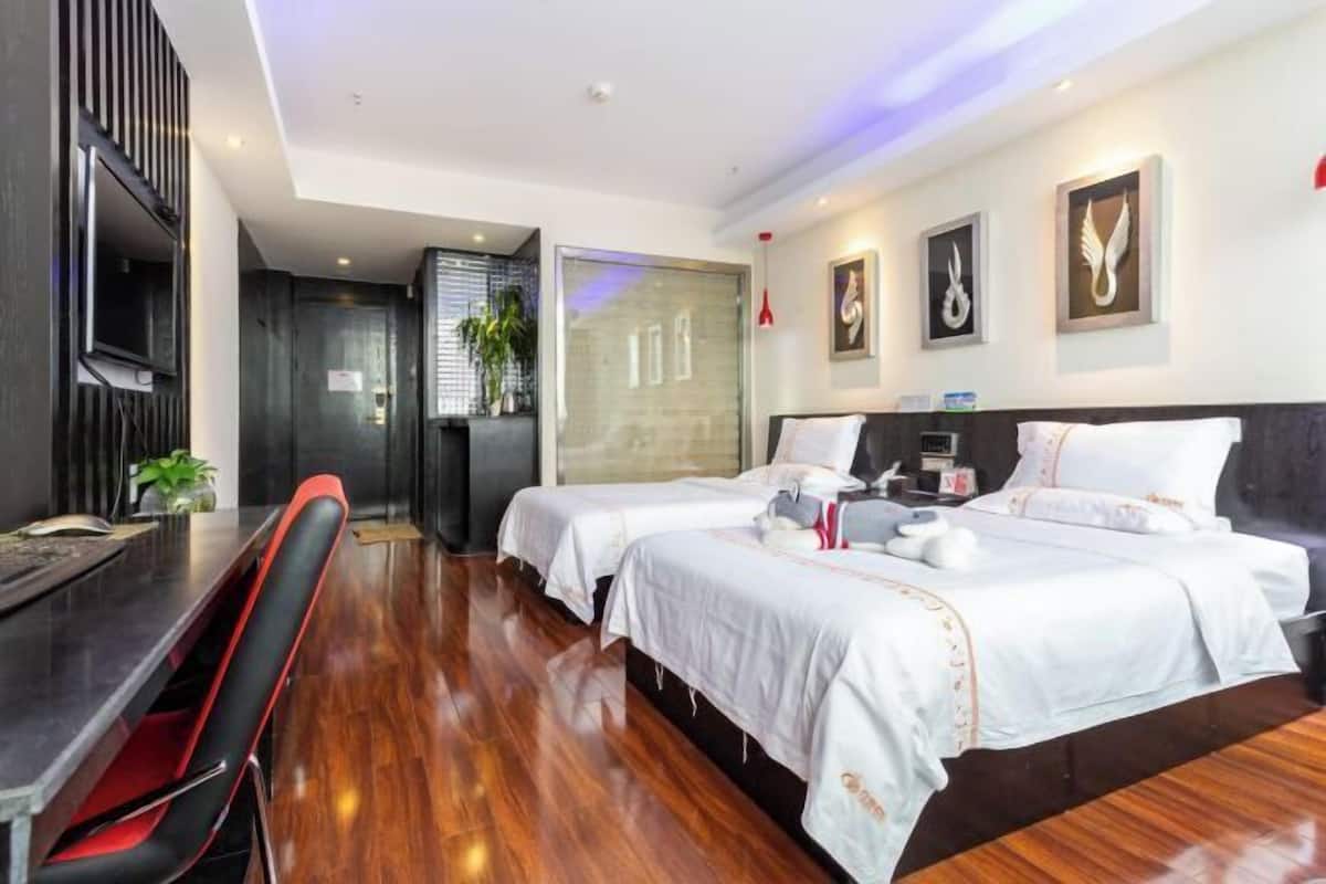 A hotel room with two beds, a desk, and a chair.