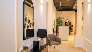 Een modern interieur met een bank, een lamp, een spiegel en een eethoek op de achtergrond.