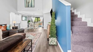 Una sala de estar moderna con una escalera, un comedor y vistas al exterior.