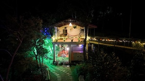 A two-story building with a balcony and a covered outdoor area, surrounded by trees and illuminated by string lights. - Tea Terrace Vythiri Resort (Vythiri)