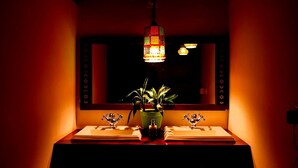 A dimly lit bathroom with two sinks, a mirror, and a hanging light fixture. - Tea Terrace Vythiri Resort (Vythiri)