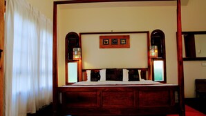 A four-poster bed with a wooden frame, white bedding, and two wall-mounted lamps. - Tea Terrace Vythiri Resort (Vythiri)