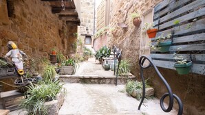 A narrow stone pathway flanked by potted plants and a rustic wooden bench. - Lo Raconet dárnes, a rural apartment in the historical center of Arnes. (Arnes)