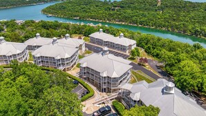 Un hotel de varios pisos con un patio central, rodeado de exuberante vegetación y vistas a un lago.