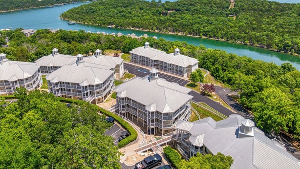 Un hotel a più piani con un cortile centrale, circondato da vegetazione rigogliosa e vista sul lago.