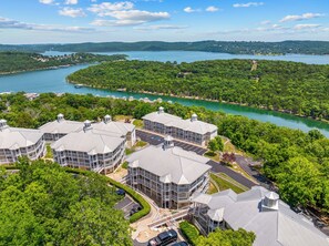 A multi-story hotel with a central courtyard, surrounded by lush greenery and a lake view. - Completely Remodeled Table Rock Retreat: Cozy Lake View Condo + Screened Porch (Kimberling City)